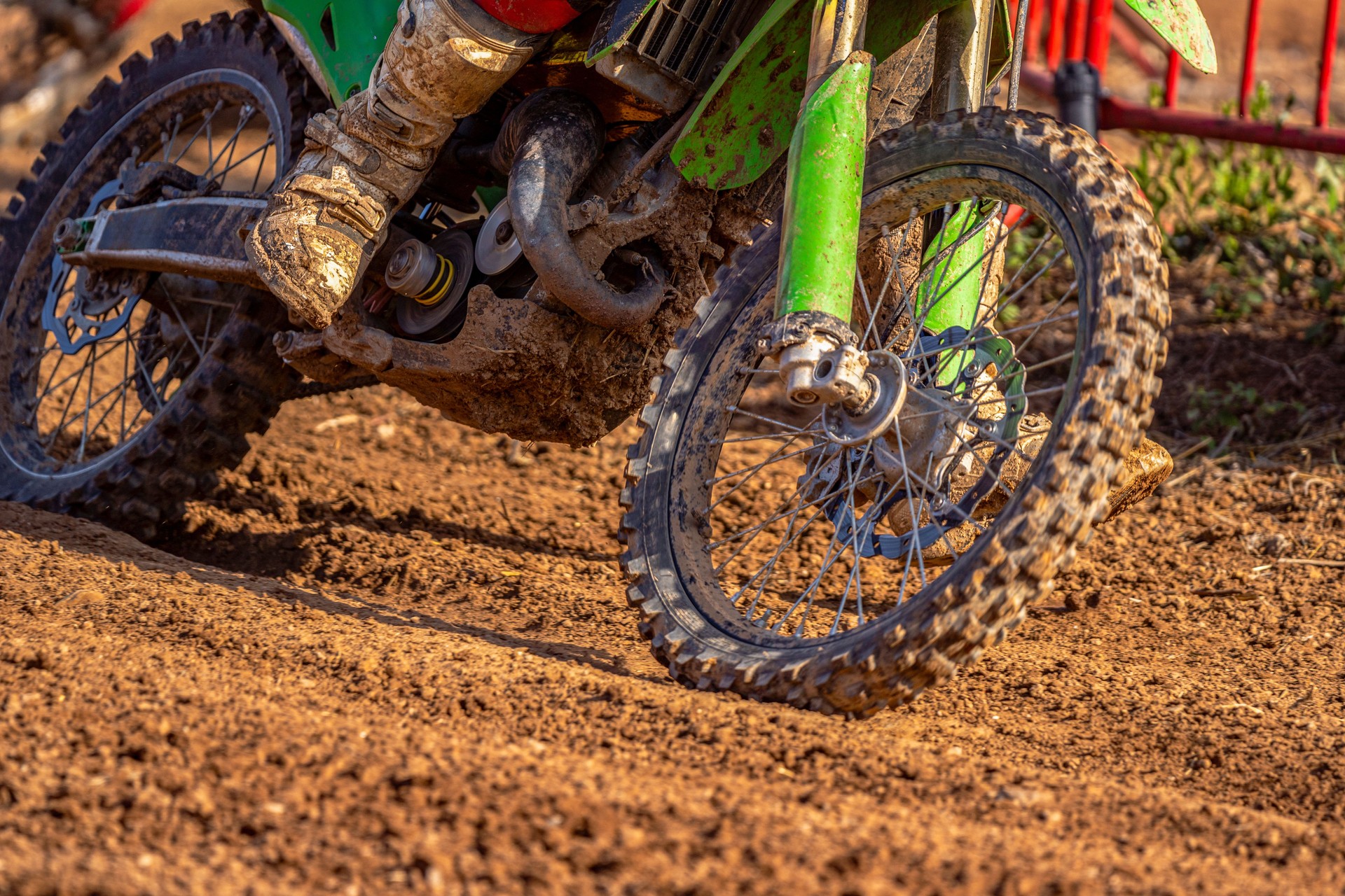 Dirty wheels, engine and boots on a muddy off-road motorcycle on a muddy off-road motorcycle on a wet dirt track in the mountains